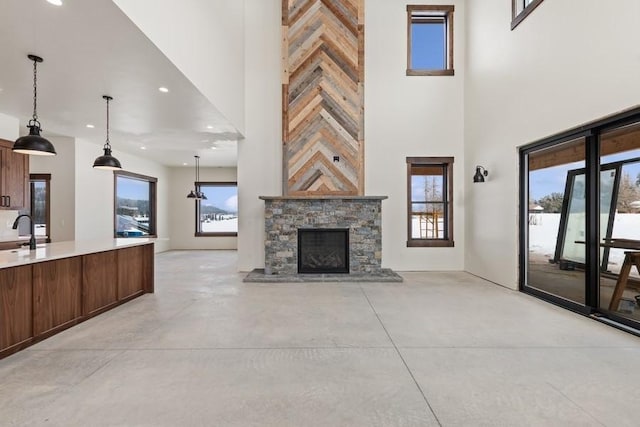 unfurnished living room with sink, a stone fireplace, and a high ceiling