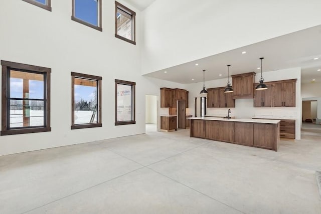 kitchen with a center island with sink, a high ceiling, and pendant lighting