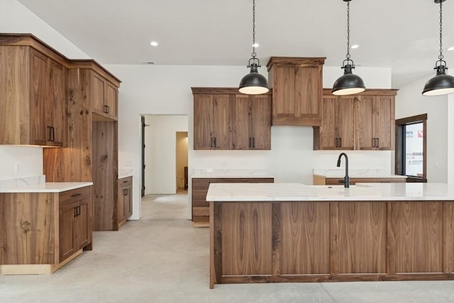 kitchen with hanging light fixtures, sink, and a center island with sink