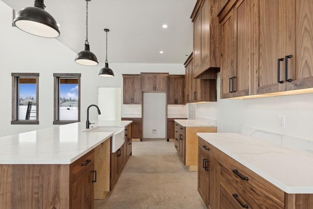 kitchen with decorative light fixtures, light stone countertops, sink, and a spacious island