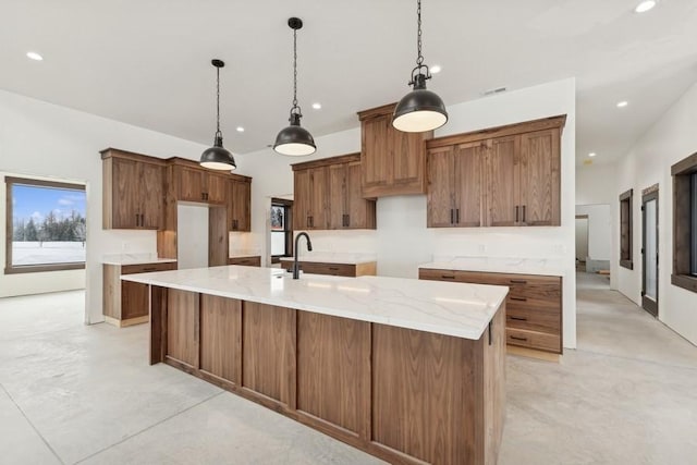 kitchen featuring light stone countertops, sink, pendant lighting, and a spacious island