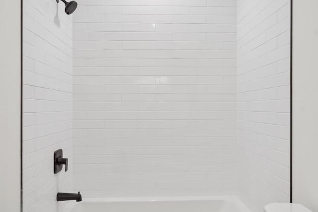 bathroom featuring tiled shower / bath and toilet