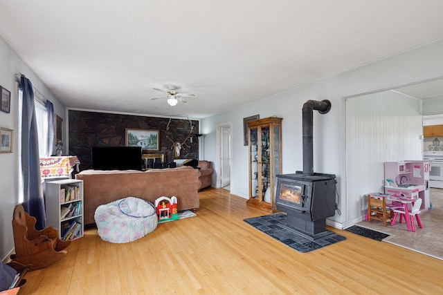 living room featuring ceiling fan, hardwood / wood-style floors, and a wood stove