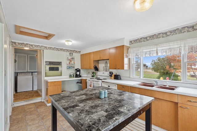 kitchen featuring washing machine and dryer, white electric stove, stainless steel oven, light tile floors, and sink