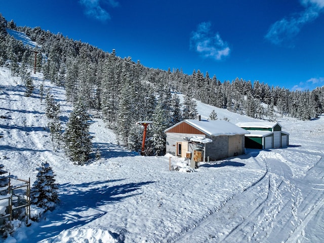 425 Lagger Gulch Rd, Anaconda, MT 59711 - snow covered back of property featuring an outdoor structure, a forest view, and a detached garage