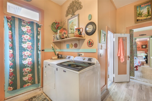 clothes washing area with washer and clothes dryer, laundry area, and light wood-style flooring