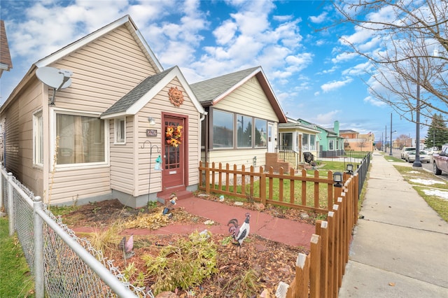 view of front of home featuring a fenced front yard, a residential view, and roof with shingles