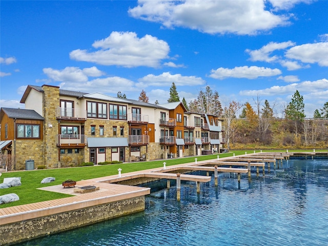 back of house featuring a water view, an outdoor fire pit, a yard, and cooling unit