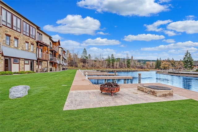 view of swimming pool featuring a yard, a fire pit, a dock, and a water view