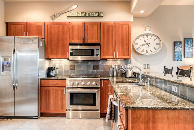 kitchen featuring sink, stone counters, appliances with stainless steel finishes, backsplash, and light tile patterned flooring