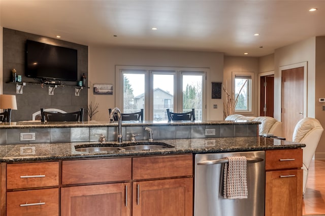 kitchen featuring dishwasher, sink, light wood-type flooring, and dark stone counters