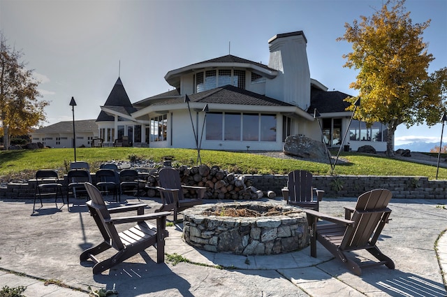 rear view of property with a yard, a patio area, and a fire pit