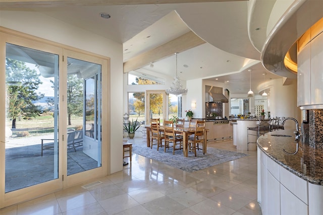 tiled dining room with lofted ceiling with beams, sink, and an inviting chandelier