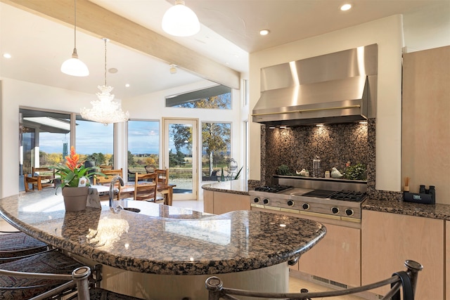 kitchen with tasteful backsplash, an island with sink, dark stone counters, pendant lighting, and wall chimney exhaust hood