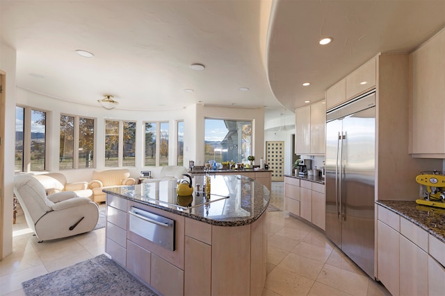 kitchen with built in refrigerator, a kitchen island, light tile patterned flooring, and cooktop