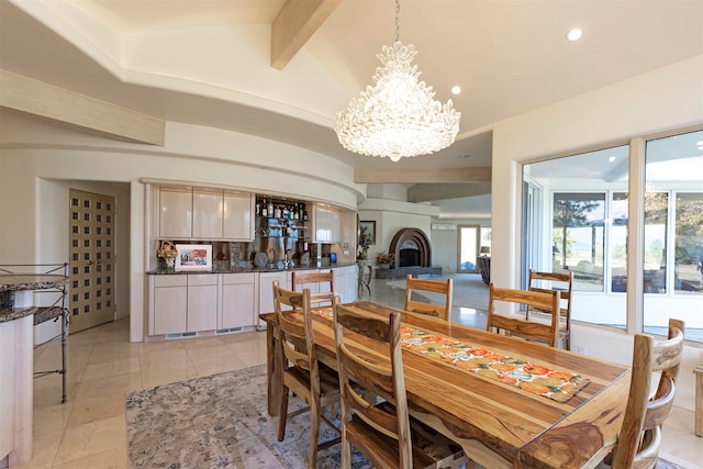 dining space with vaulted ceiling with beams, an inviting chandelier, and light tile patterned floors