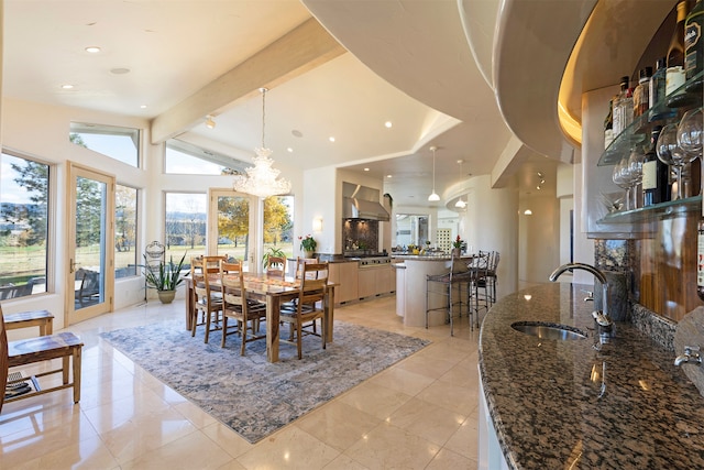 dining area with vaulted ceiling with beams, a notable chandelier, sink, and light tile patterned floors