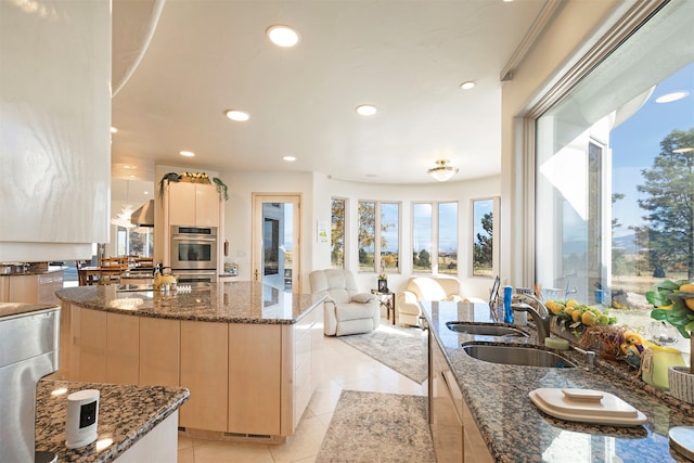 kitchen featuring stainless steel double oven, dark stone countertops, sink, a center island, and light tile patterned floors