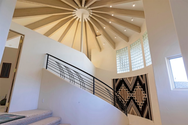 staircase featuring beamed ceiling and a high ceiling