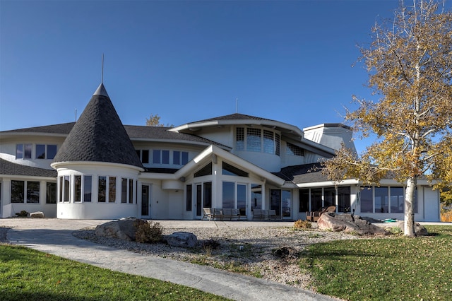 rear view of property with a sunroom, a lawn, and a patio area