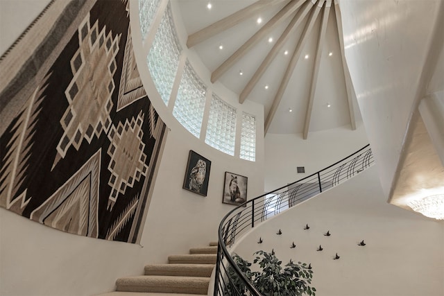 staircase featuring beam ceiling and a towering ceiling