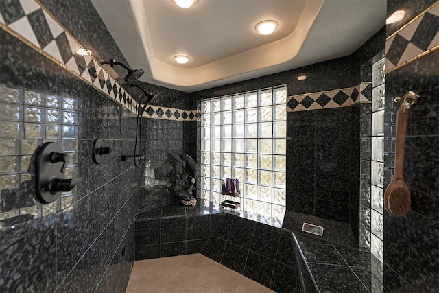 bathroom featuring tile walls, a tile shower, and a tray ceiling