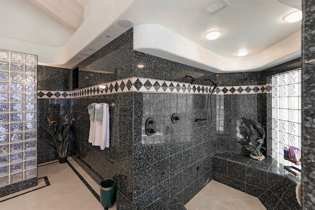 bathroom with a tile shower and tile walls