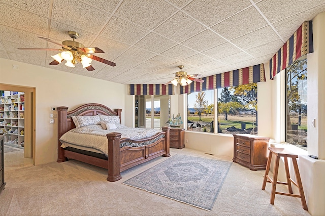 carpeted bedroom with a drop ceiling and ceiling fan