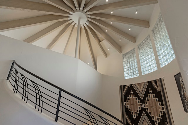 staircase with beam ceiling and high vaulted ceiling