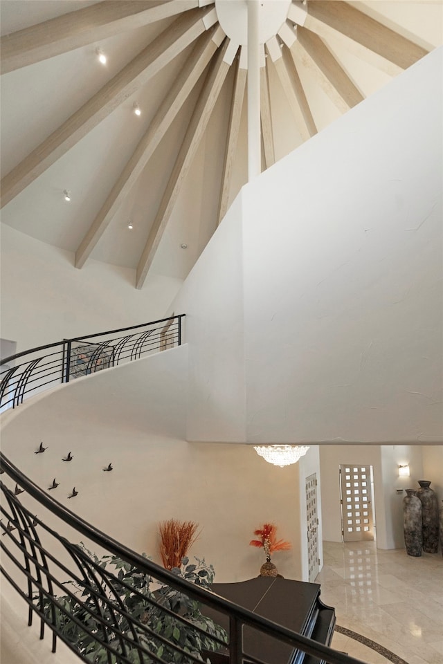 stairs featuring beam ceiling, high vaulted ceiling, and a chandelier