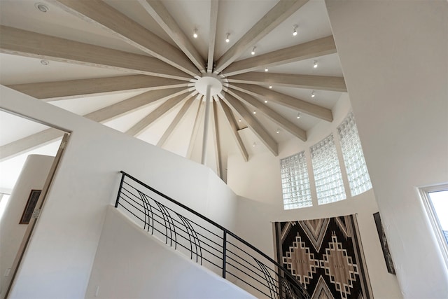 stairway with beamed ceiling and a towering ceiling