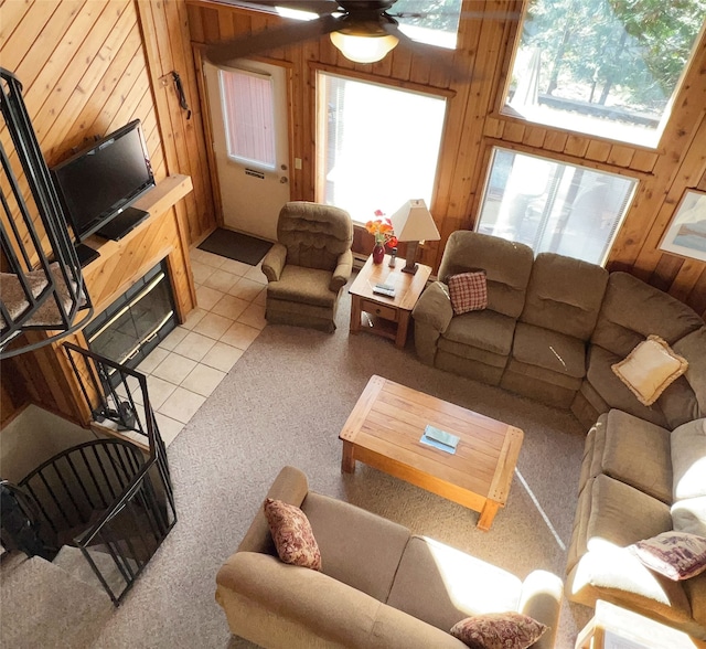 carpeted living room featuring ceiling fan and wooden walls