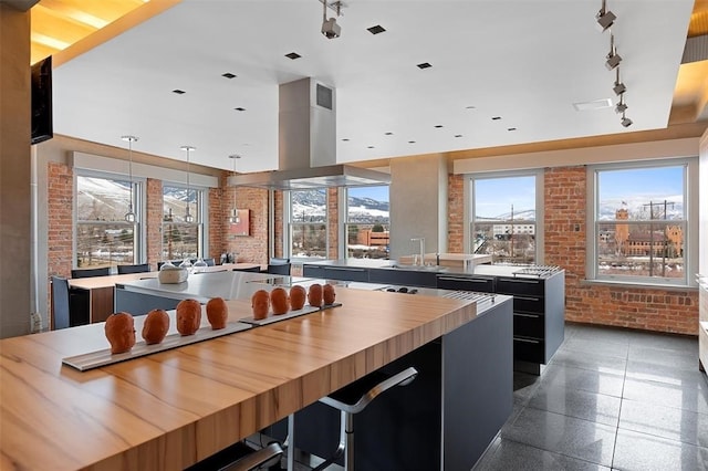 kitchen with a kitchen island, brick wall, and island exhaust hood