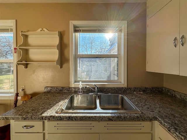 kitchen with white cabinets, dark stone countertops, and sink