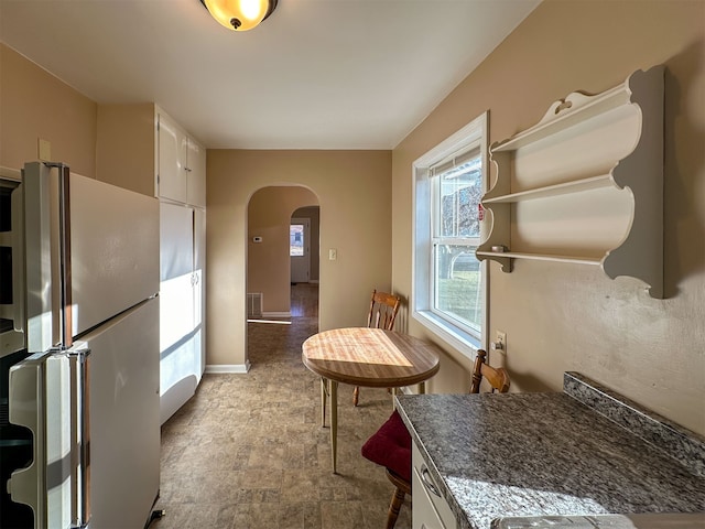 kitchen featuring light tile floors, white cabinetry, and stainless steel refrigerator