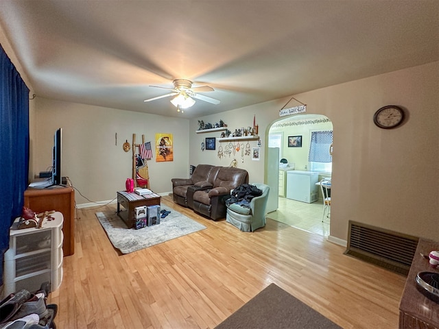 living room with washer and clothes dryer, ceiling fan, and light hardwood / wood-style flooring