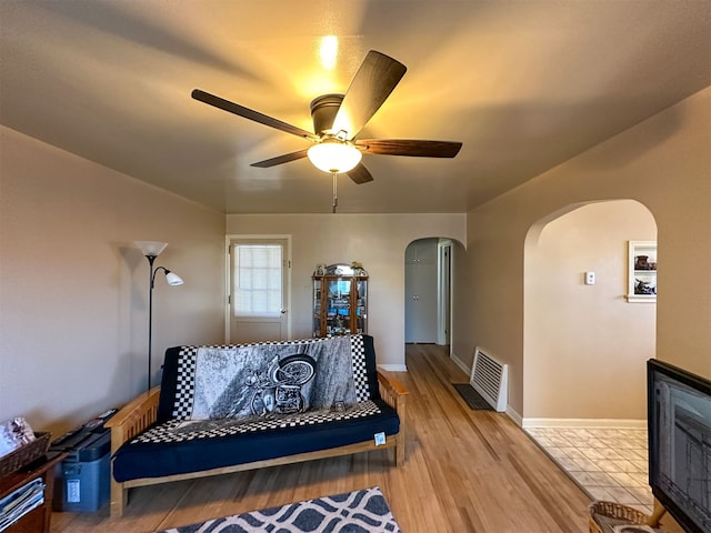 tiled bedroom with ceiling fan and a fireplace