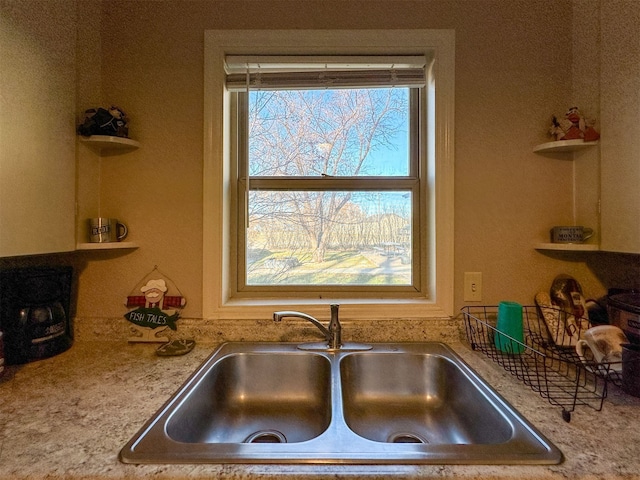 kitchen featuring sink, light stone counters, and a healthy amount of sunlight