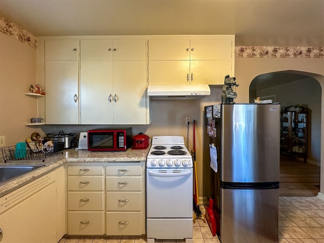 kitchen with white stove, white cabinetry, light stone countertops, light tile flooring, and stainless steel refrigerator