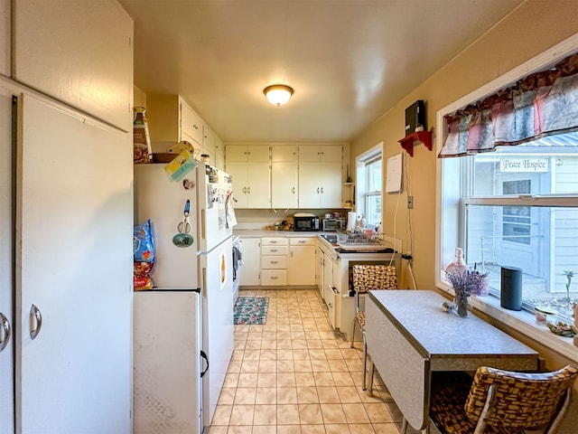 kitchen featuring white fridge, white cabinetry, and light tile floors