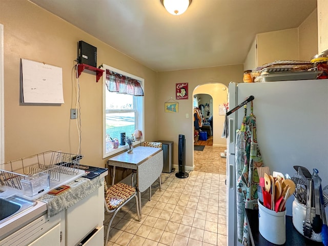 kitchen with refrigerator, white cabinetry, and light tile floors