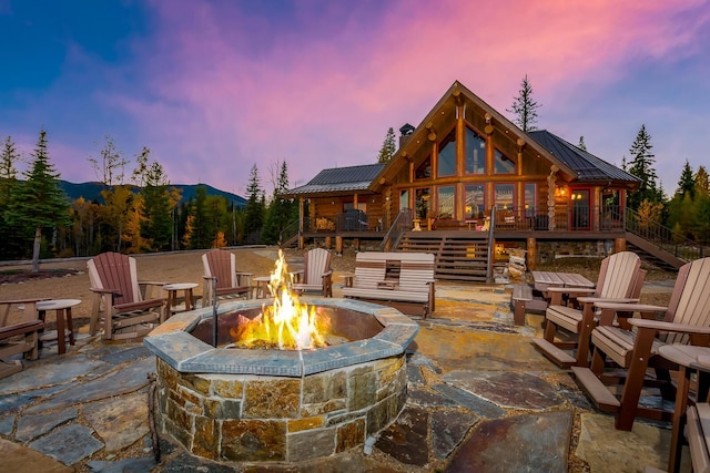 rear view of property with stairway, a wooden deck, a patio, a fire pit, and metal roof