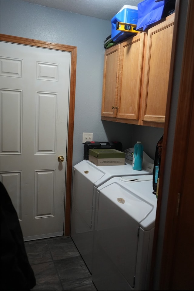 laundry room featuring cabinets, dark tile floors, and washing machine and clothes dryer