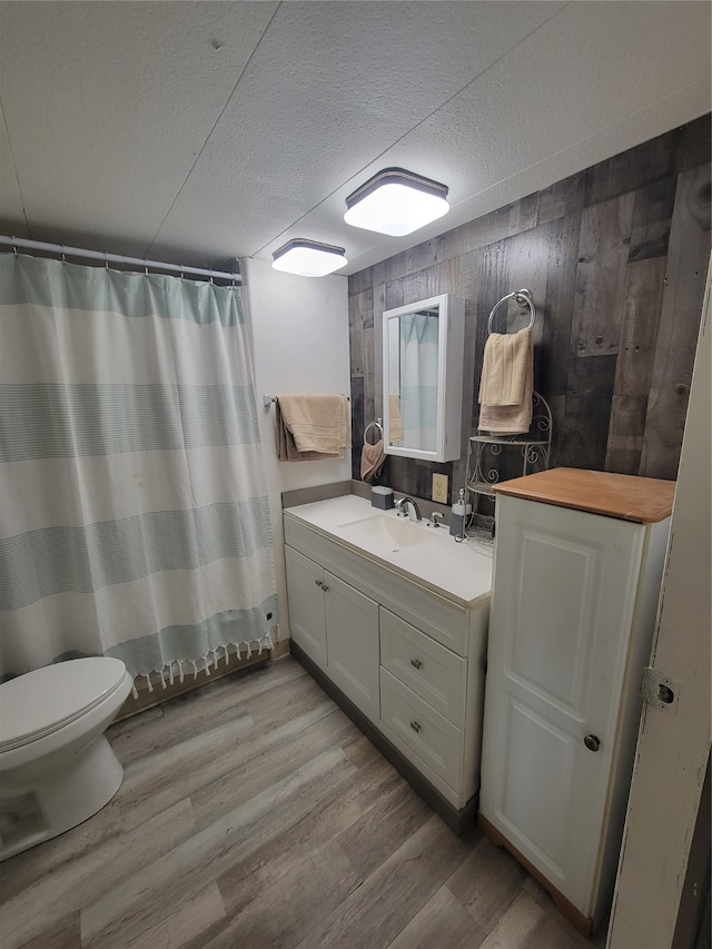 bathroom with vanity, wood-type flooring, a shower with curtain, wood walls, and toilet