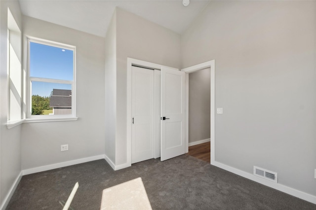 unfurnished bedroom with dark colored carpet and a closet