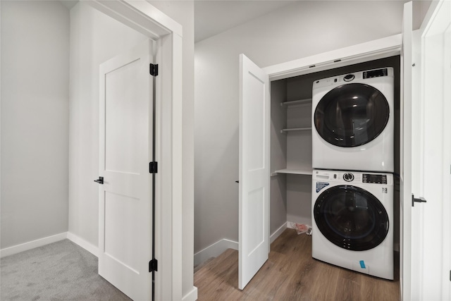 clothes washing area featuring stacked washer and dryer and hardwood / wood-style flooring