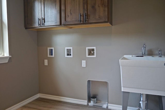 clothes washing area featuring dark wood-style flooring, hookup for a washing machine, cabinet space, a sink, and baseboards