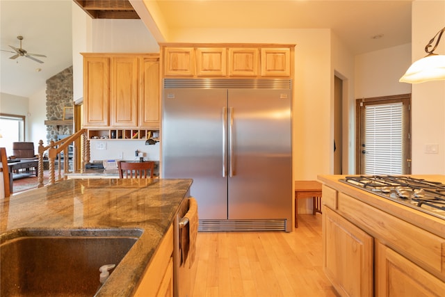 kitchen with lofted ceiling, ceiling fan, appliances with stainless steel finishes, decorative light fixtures, and light hardwood / wood-style floors