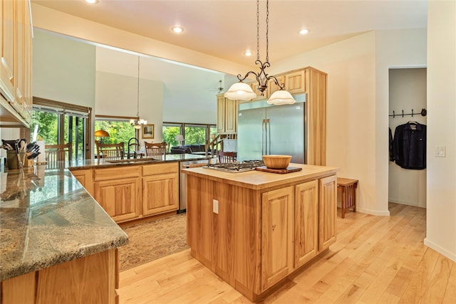 kitchen featuring stainless steel appliances, a kitchen island, a healthy amount of sunlight, and sink