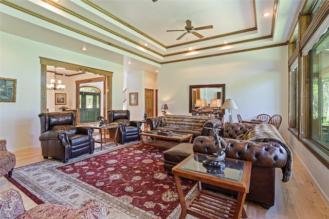 living room featuring ceiling fan with notable chandelier, hardwood / wood-style flooring, a raised ceiling, and plenty of natural light